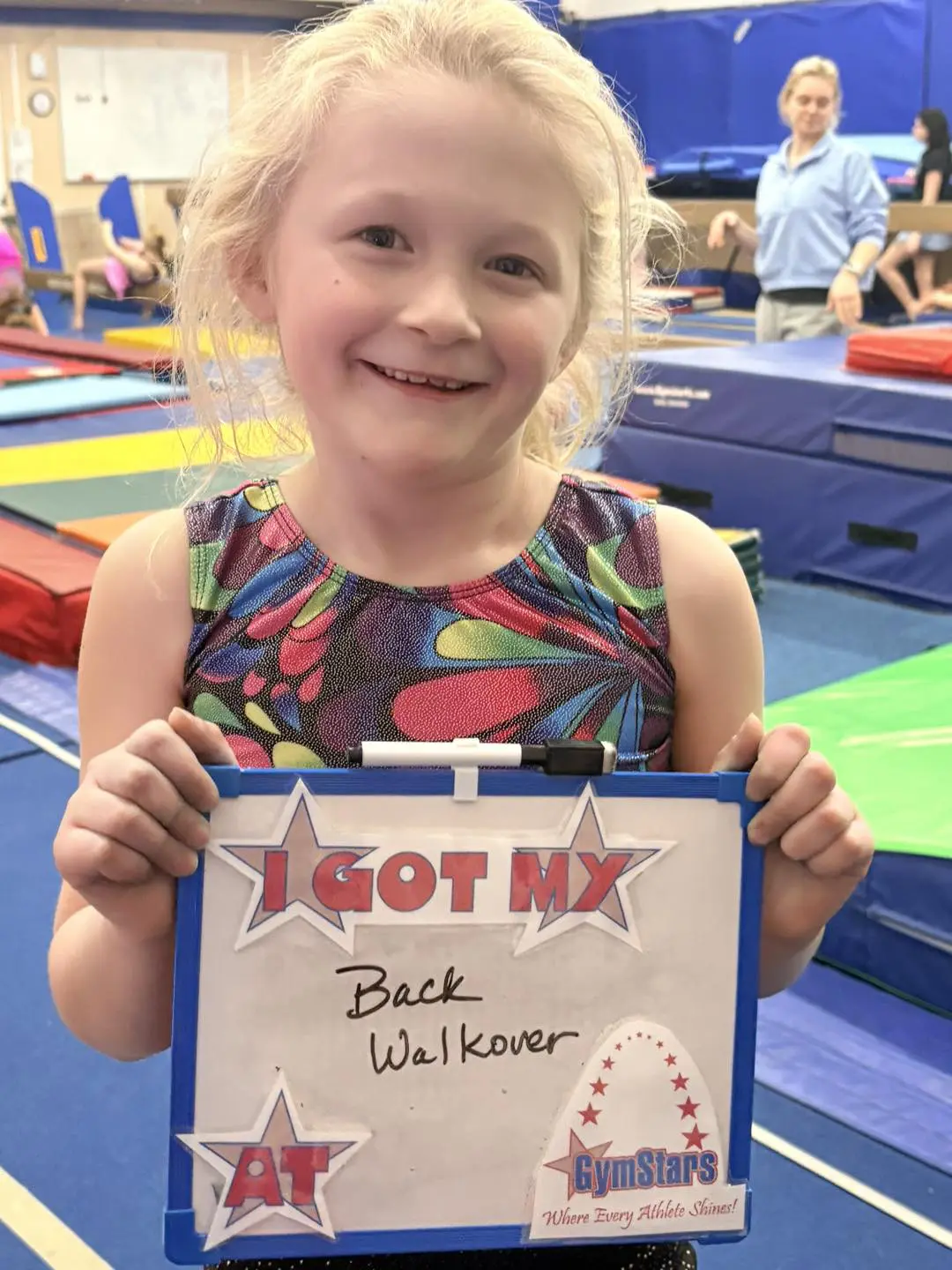 Smiling young gymnast holding achievement board