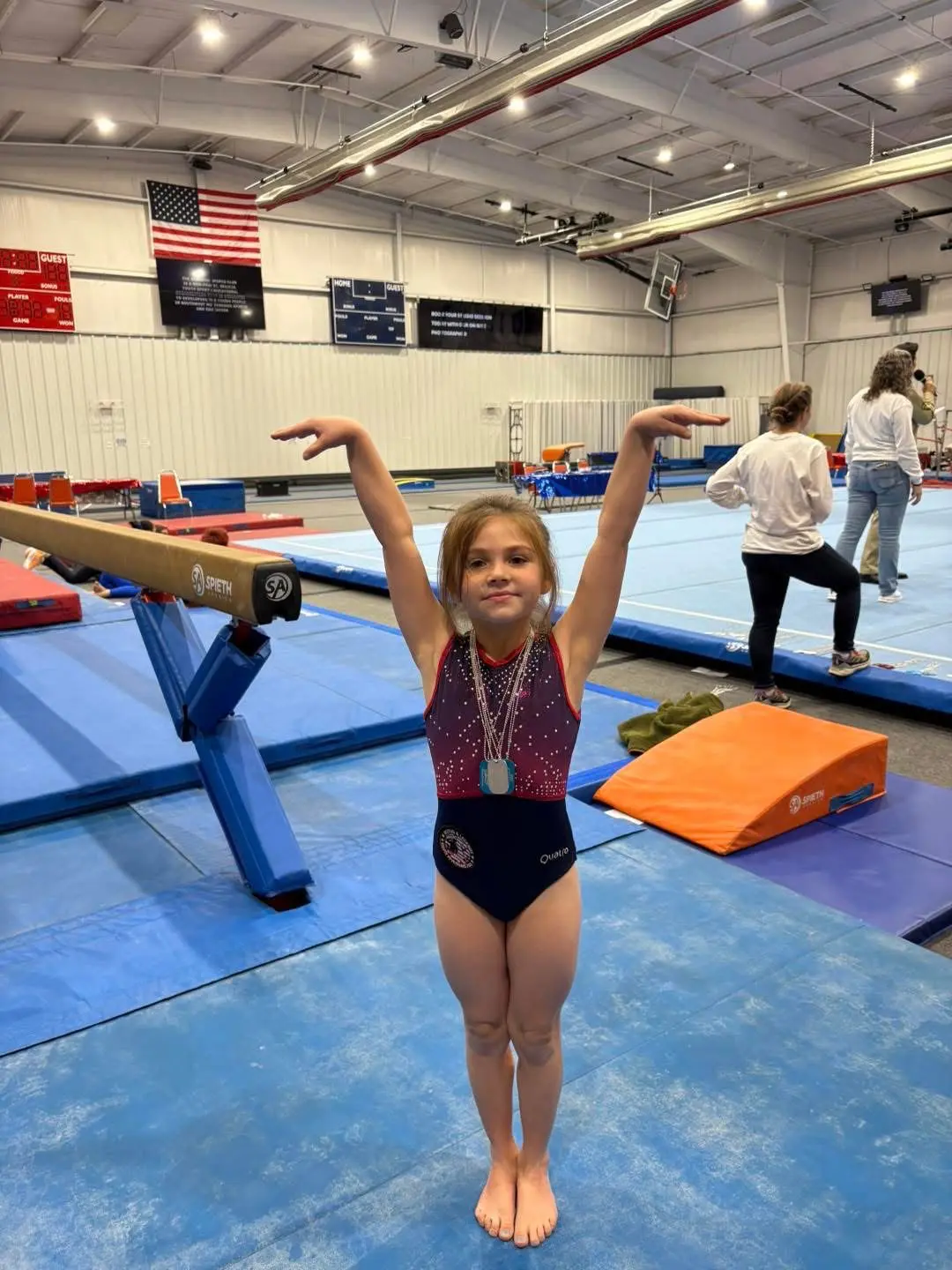 Young gymnast posing with medal near balance beam