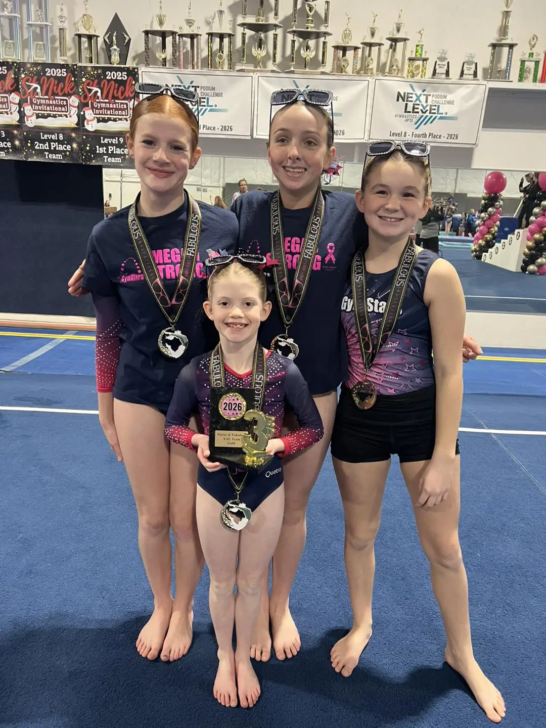 Young gymnasts smiling with medals and trophy