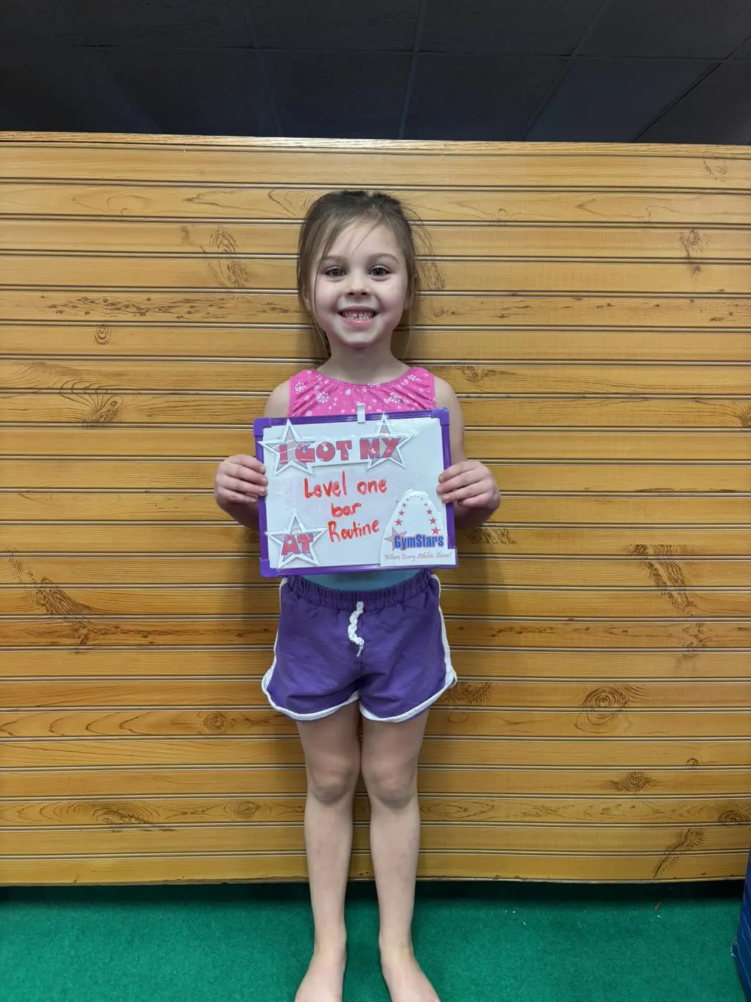 Smiling girl holding Level One gymnastics certificate