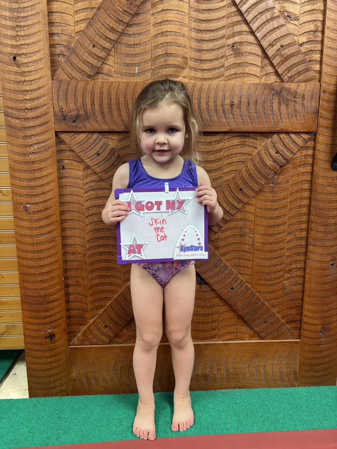 Young gymnast holding certificate in purple leotard
