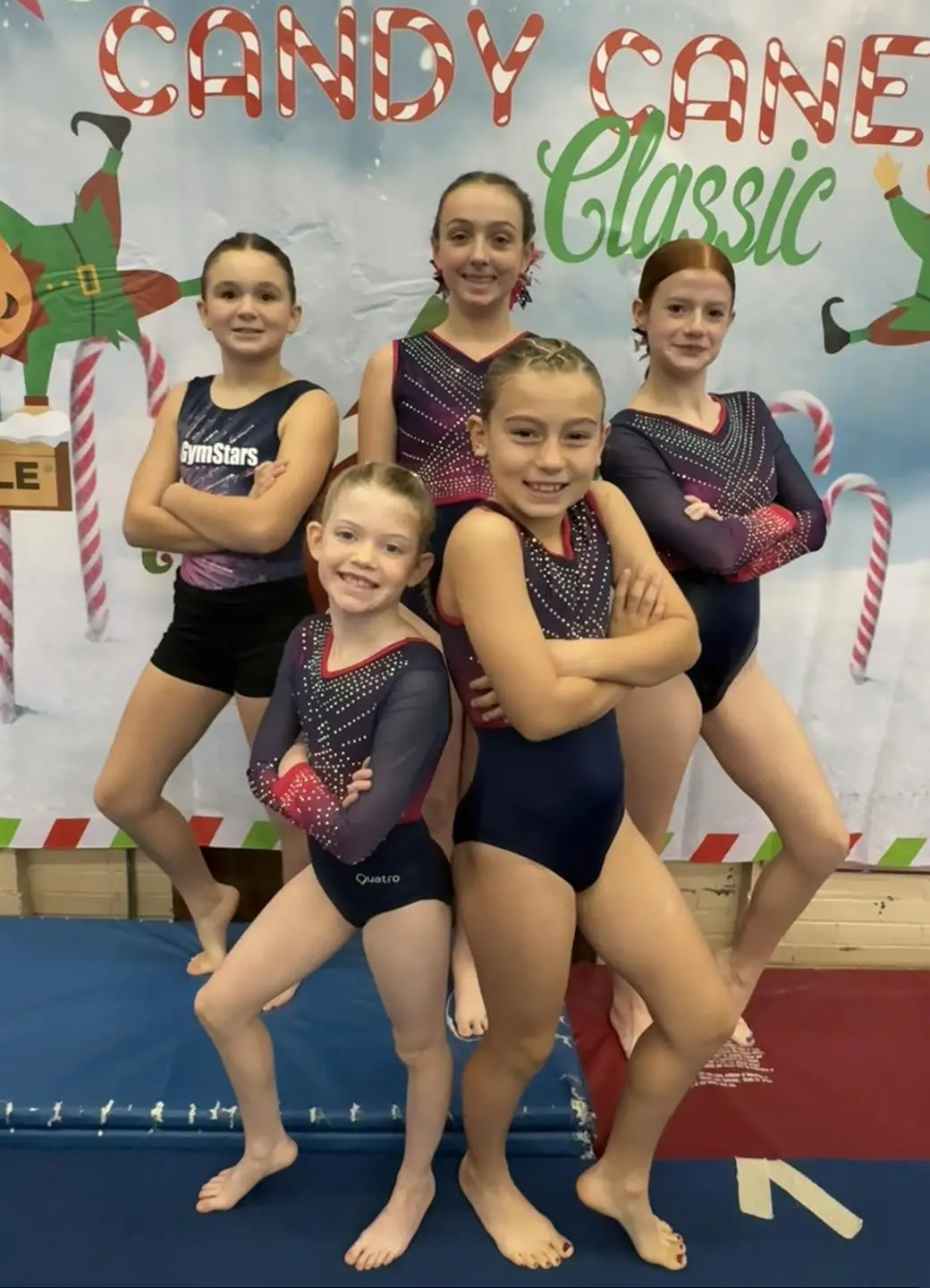 Five smiling gymnasts in colorful leotards